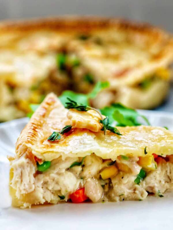 slice of air fryer chicken pot pie on a plate with a full chicken pot pie behind it.