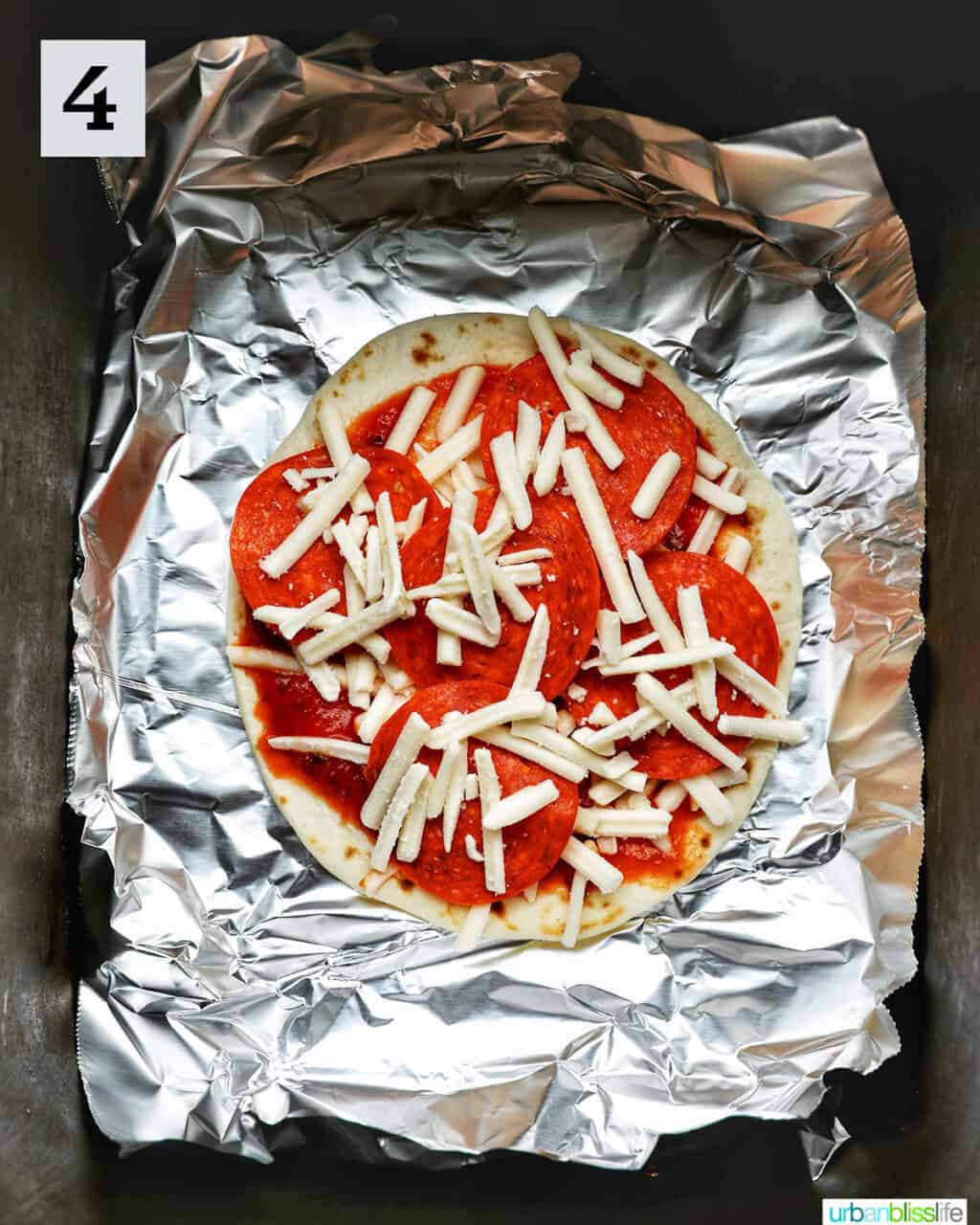 mini pizza on top of aluminum foil in an air fryer basket.