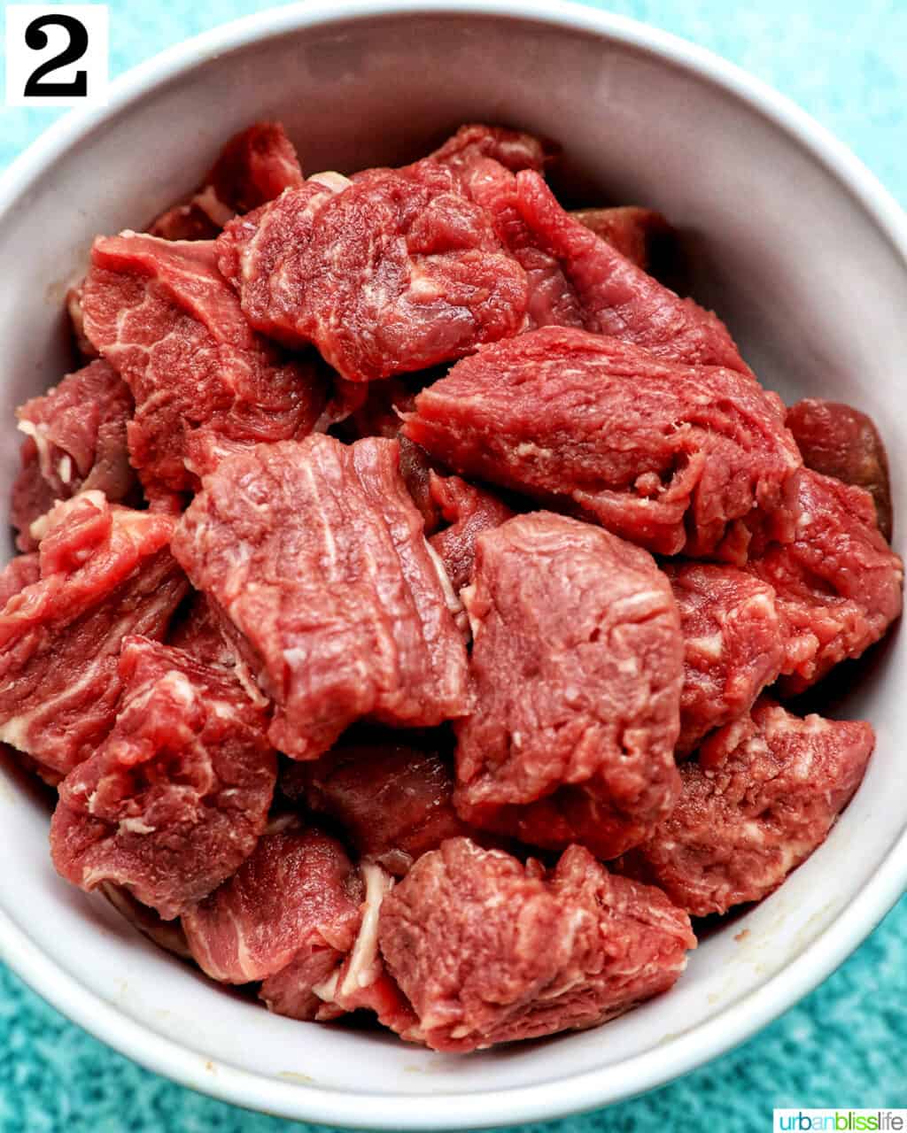 raw steak bites chopped and placed in a white bowl.