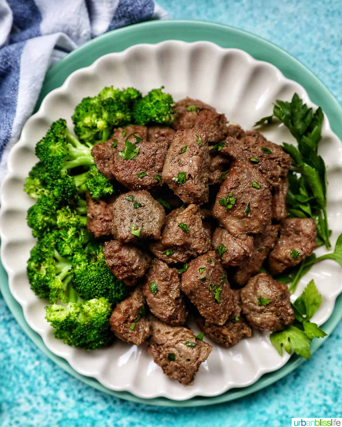 air fryer steak bites with chopped parsley garnish and a side of broccoli on a plate.