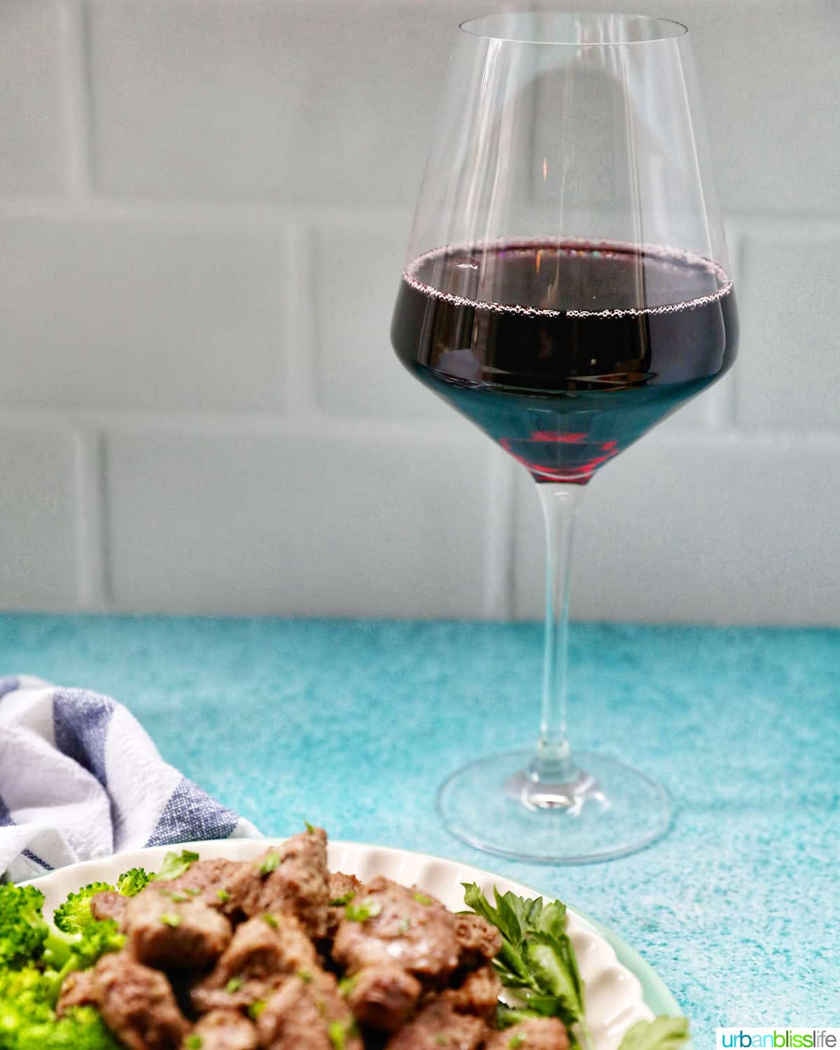 air fryer steak bites with a glass of dark red wine behind it.