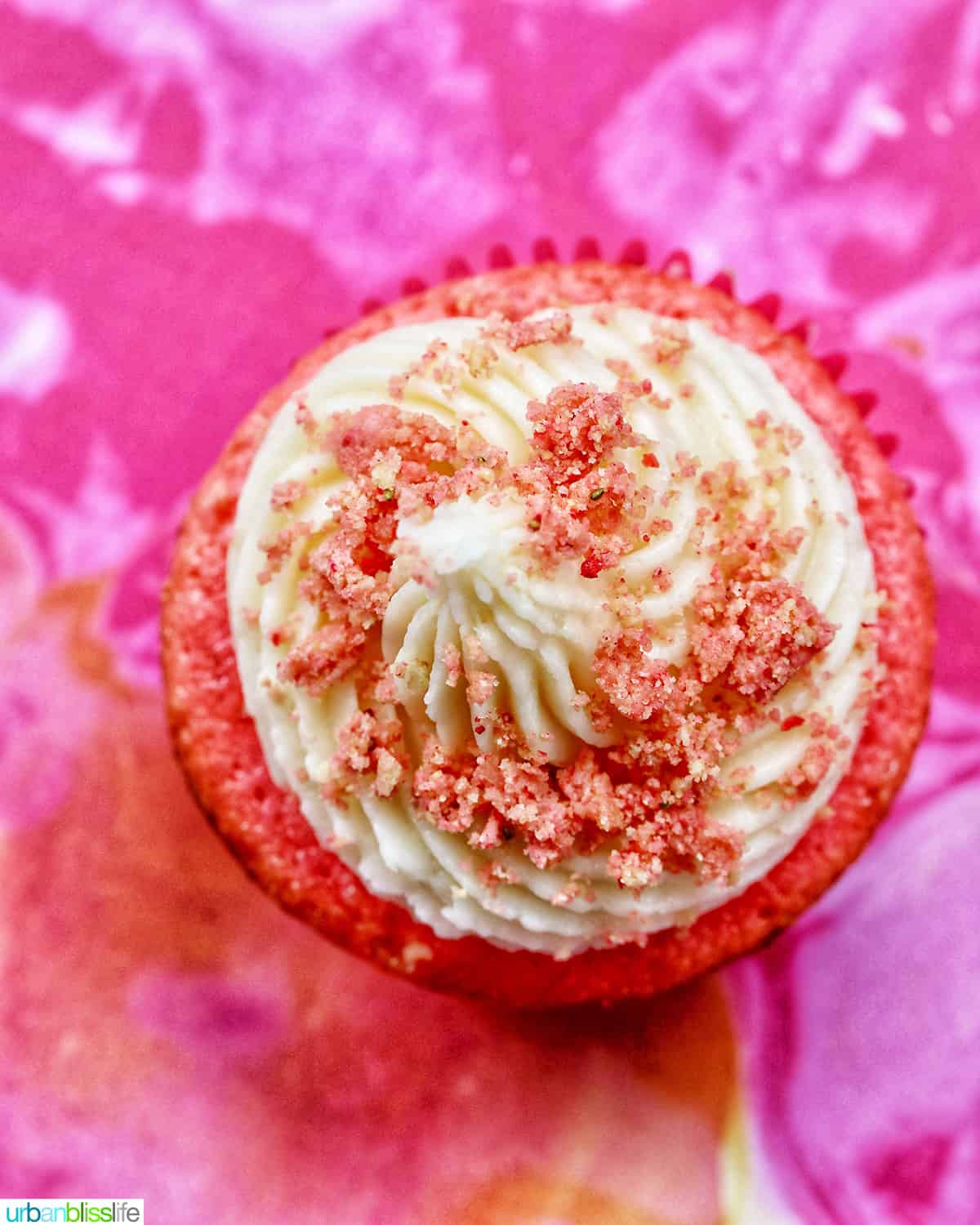 strawberry crunch cupcake on a bright pink swirled background.
