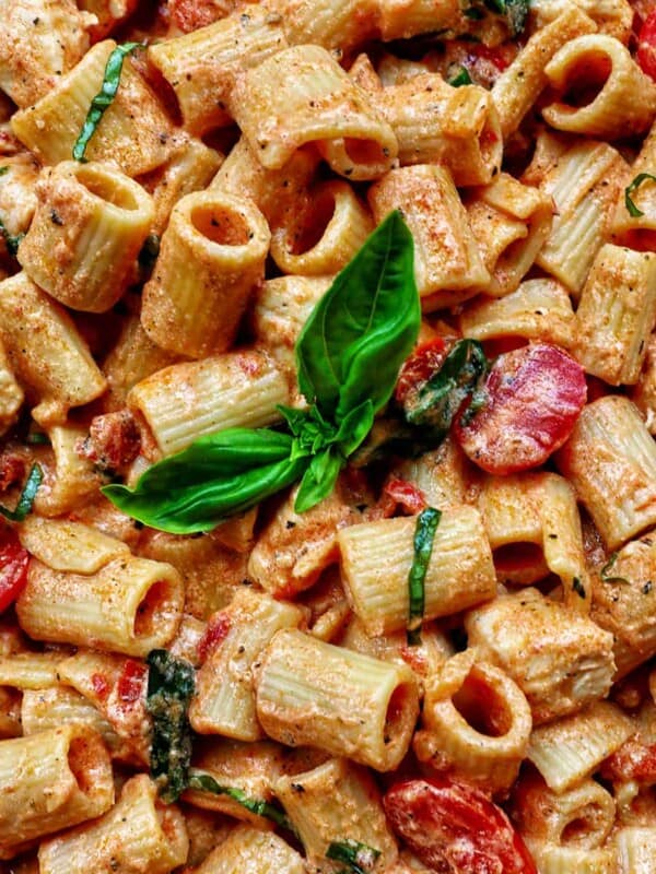 rigatoni pasta in a creamy Tuscan sauce with chicken, tomatoes, and herbs.