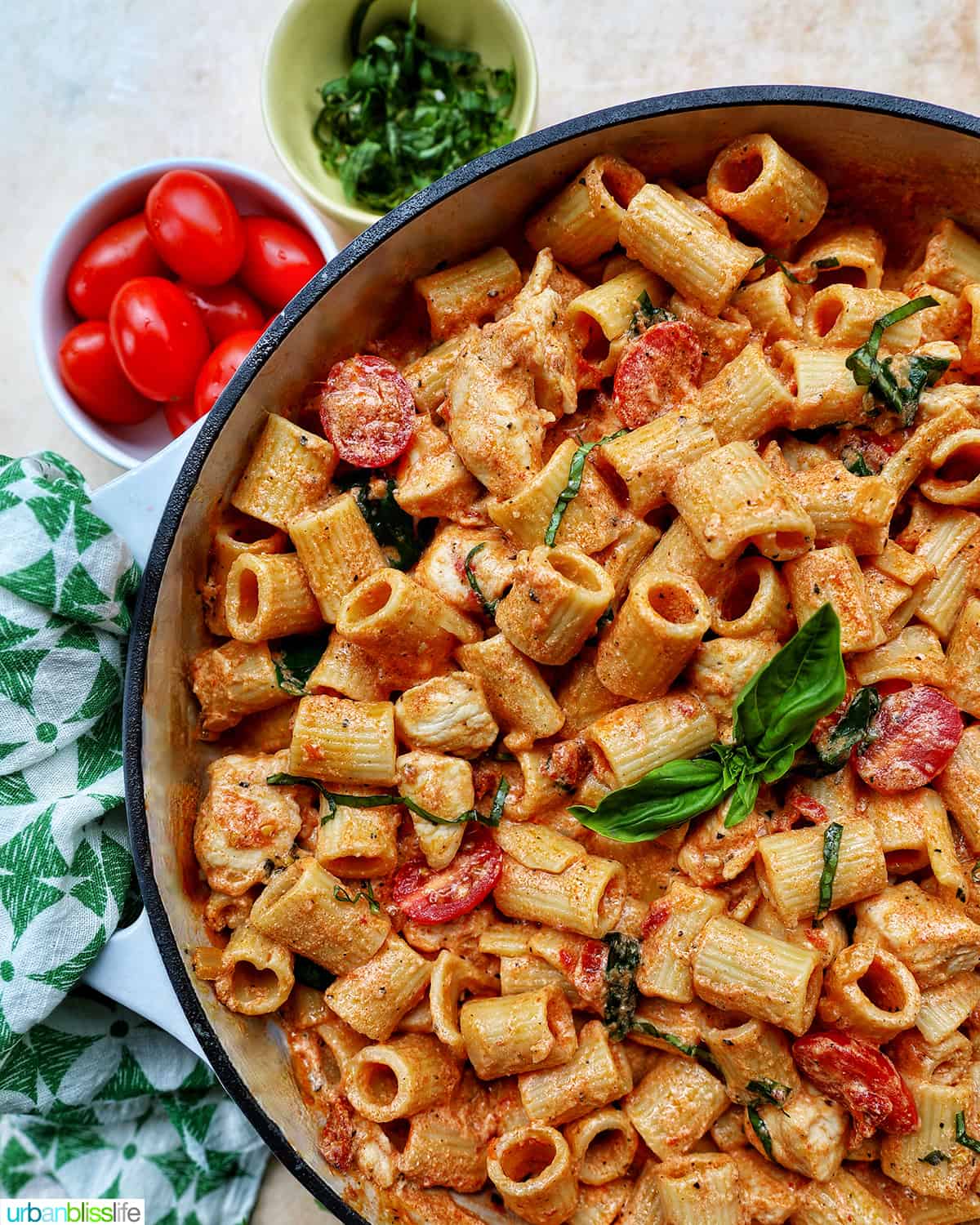 large saucepan with rigatoni pasta in a creamy Tuscan sauce with chicken, tomatoes, and herbs.