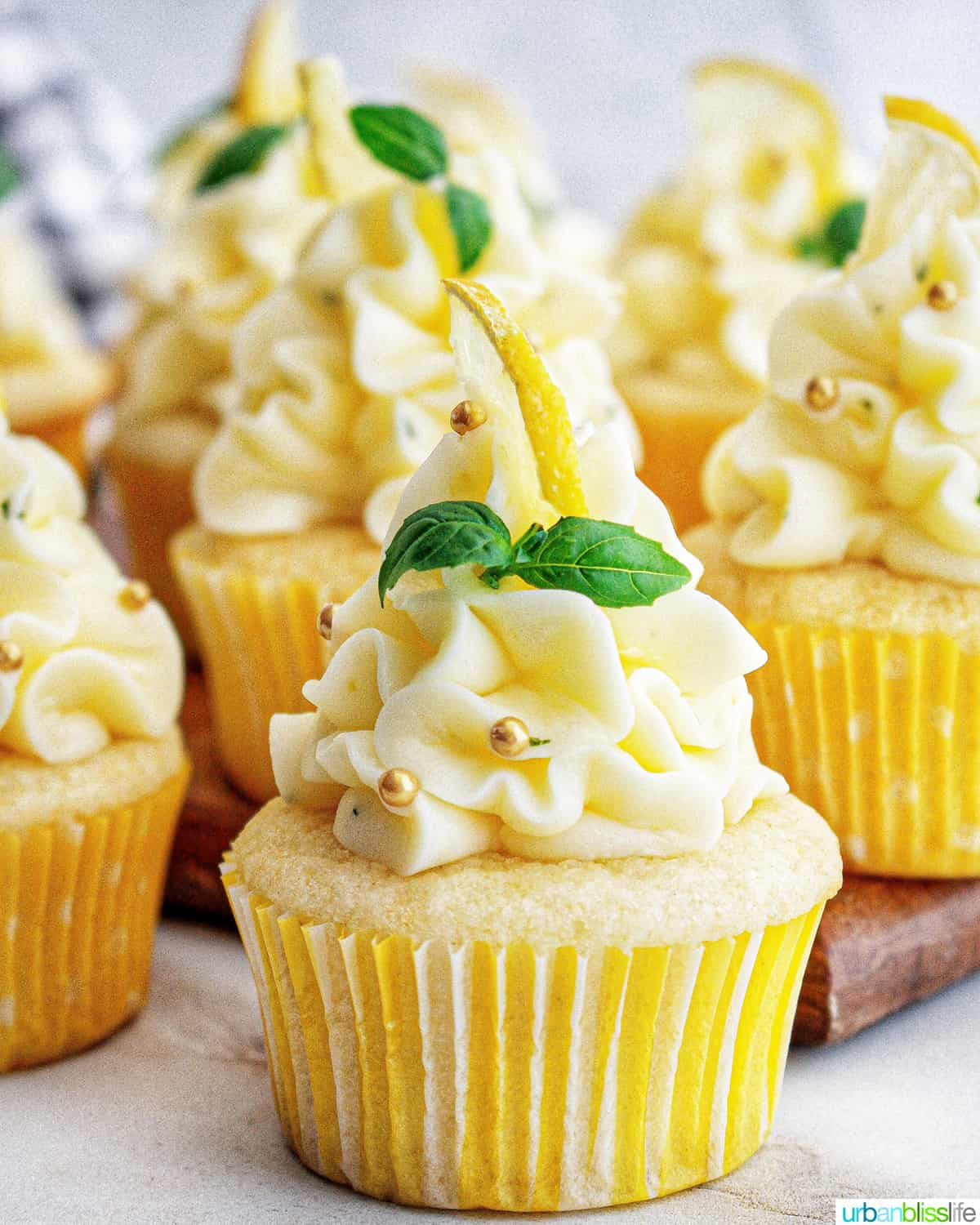 group of lemon basil cupcakes with basil leaf garnishes.