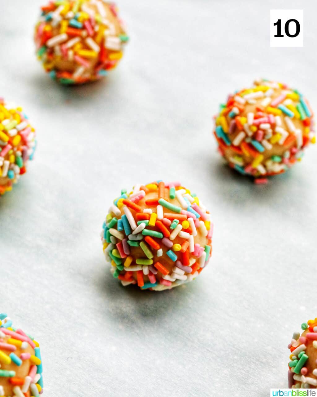 almond sugar cookie dough coated with sprinkles on parchment paper.