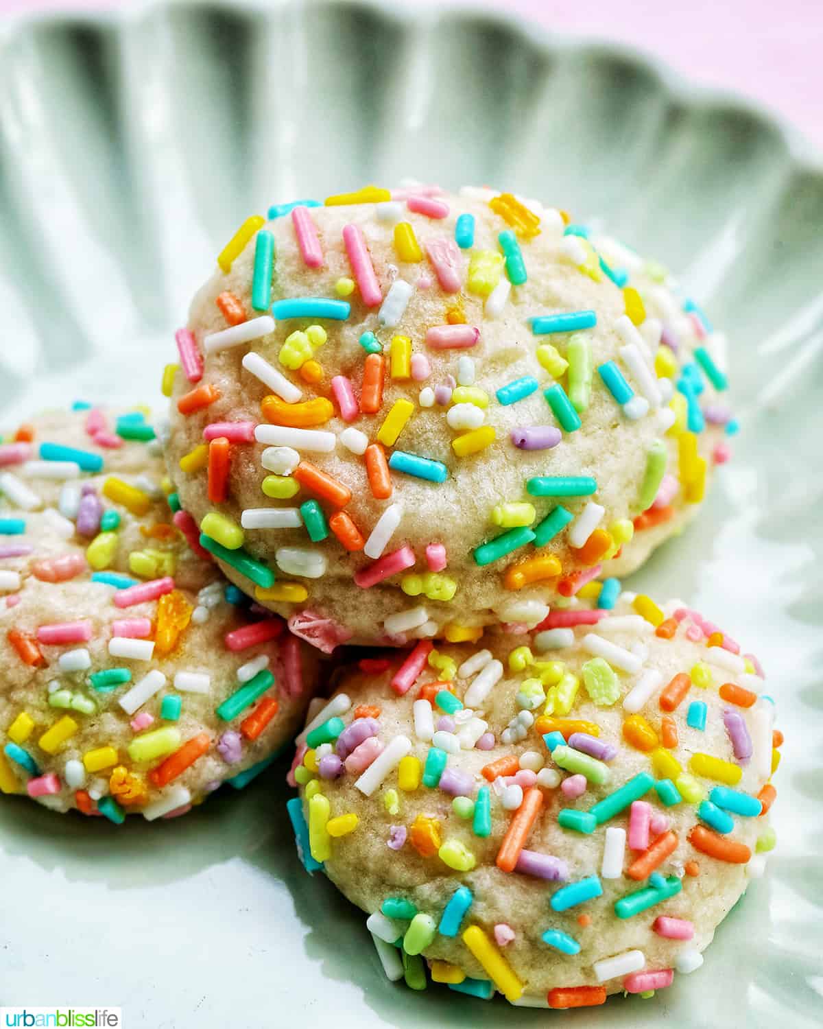 several spring almond sprinkle cookies stacked on top of one another.