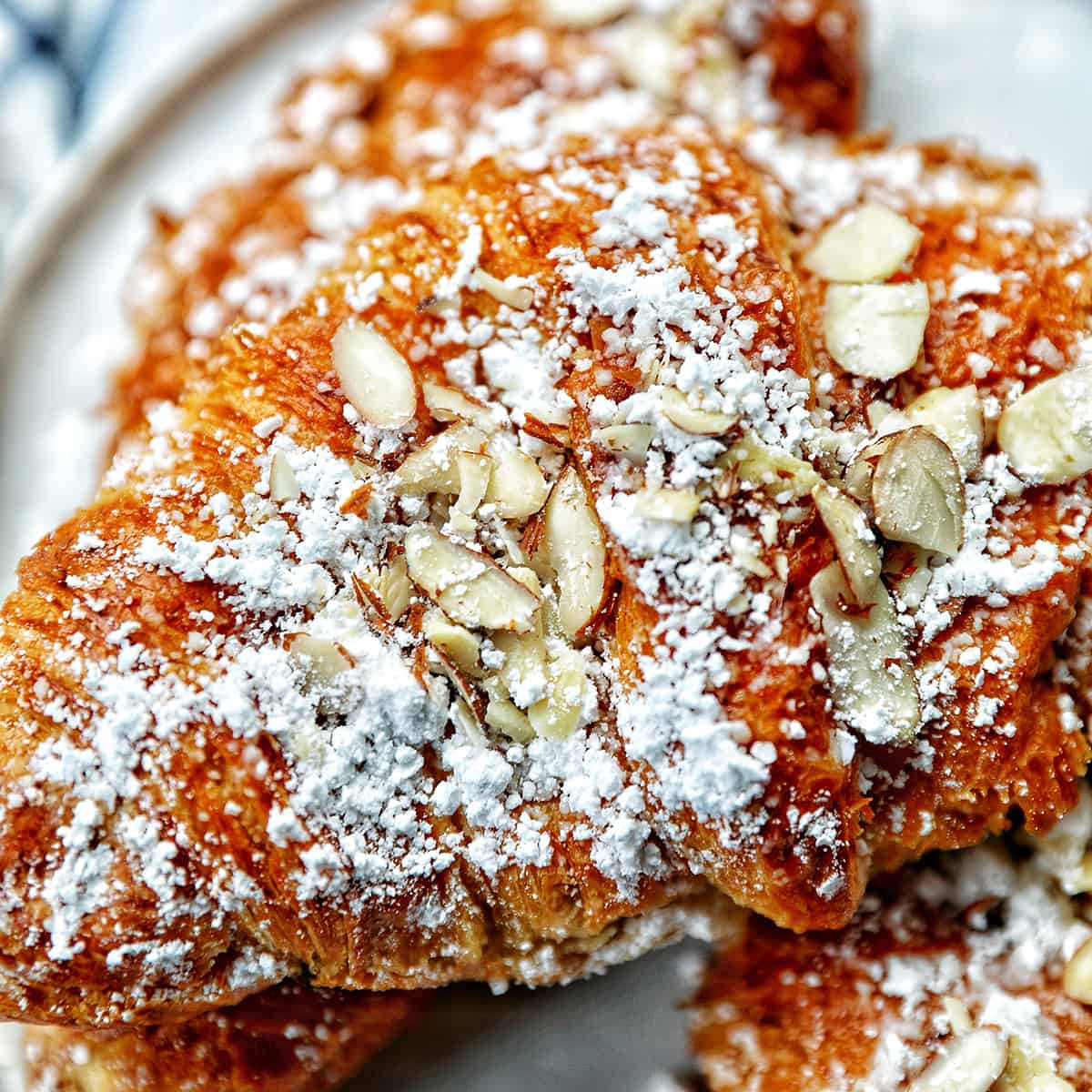 stack of almond croissants on a plate.