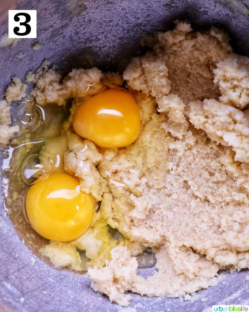 egg yolks added to butter sugar mixture in a stainless steel bowl.