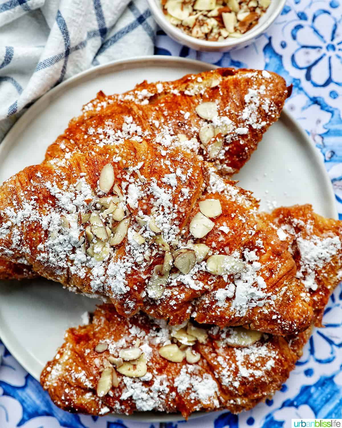 three almond croissants on a plate.