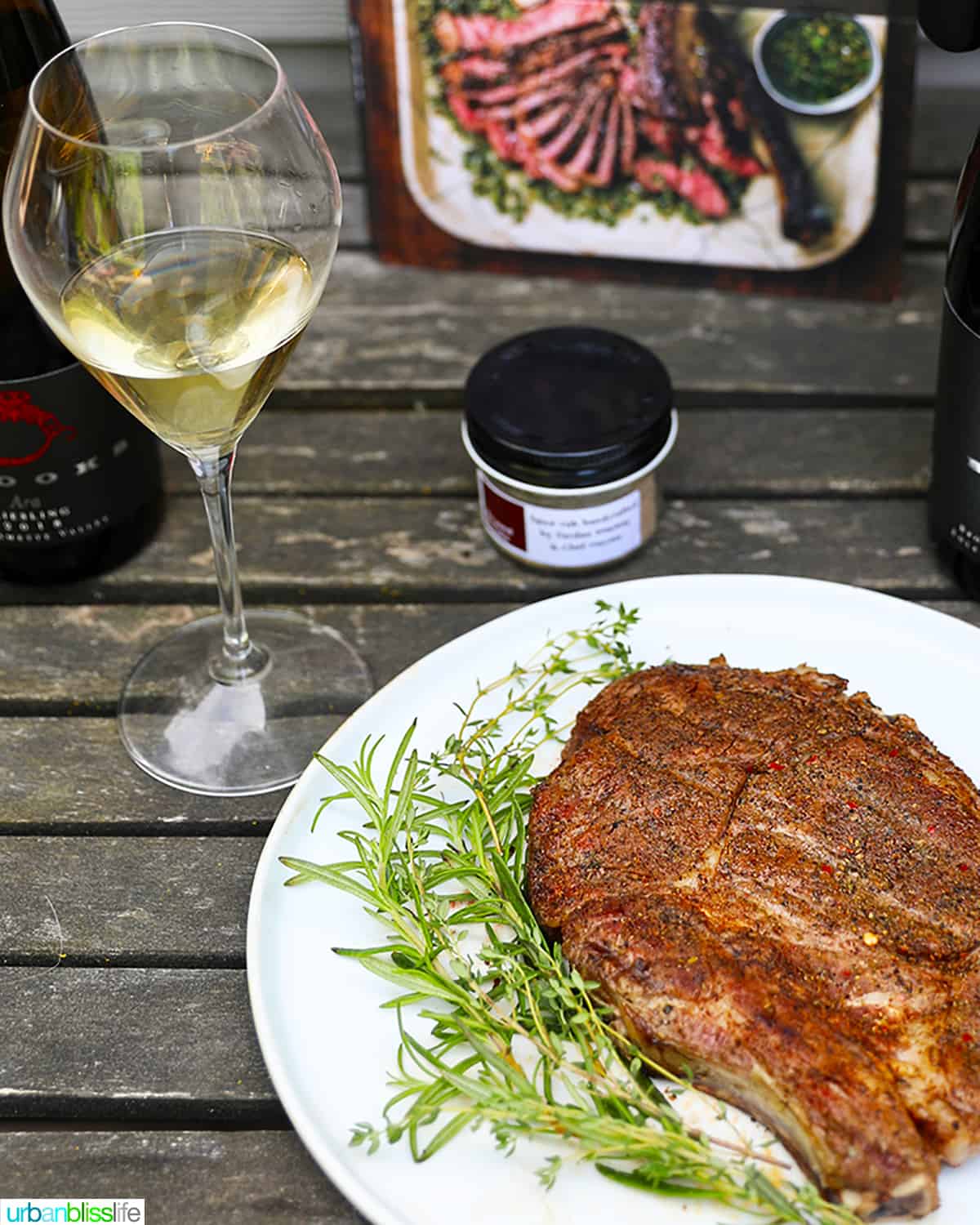 glass of white wine next to a steak.