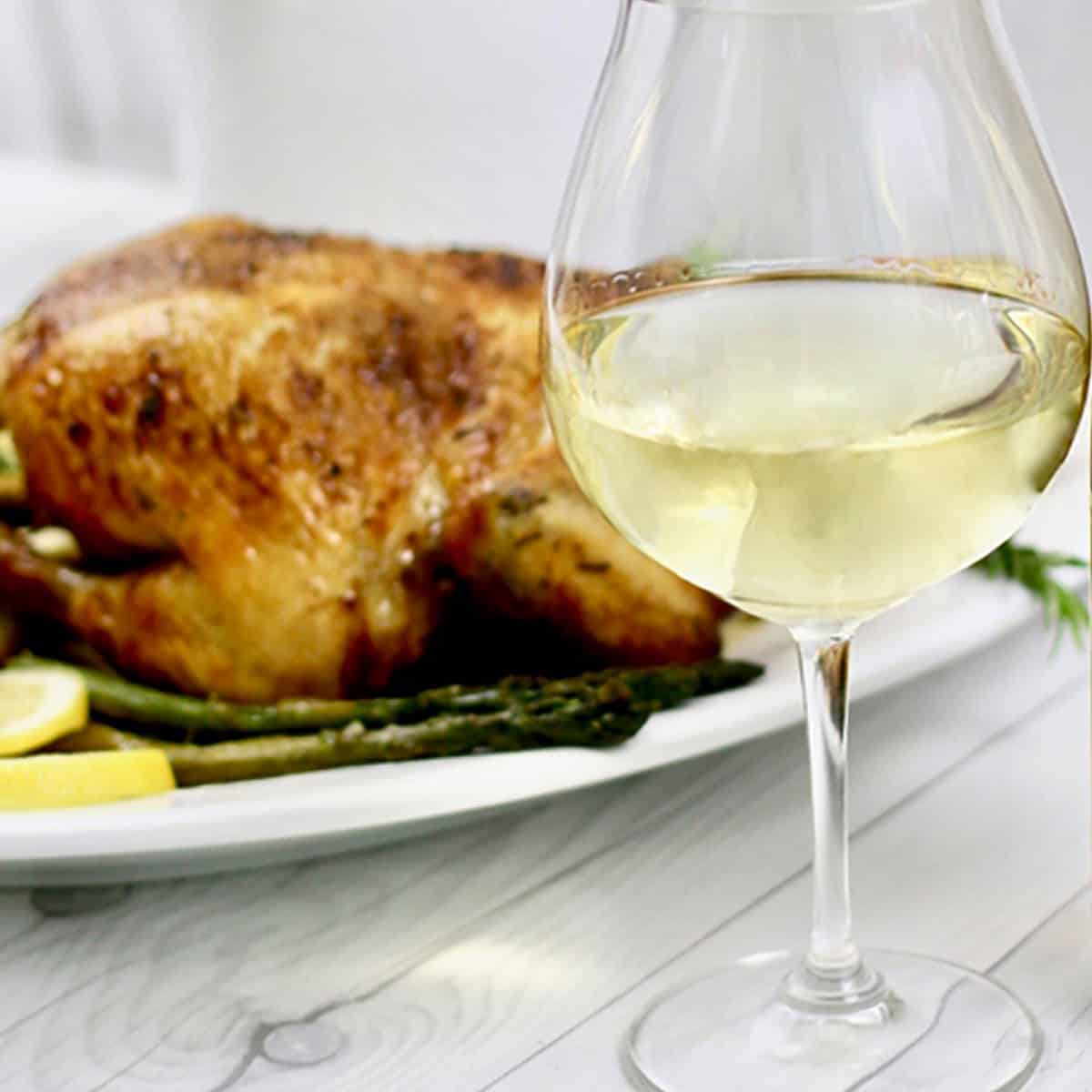 glass of chardonnay in front of a roast chicken.