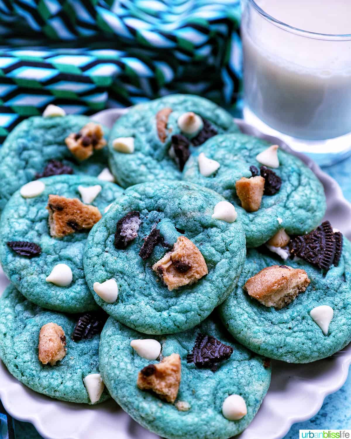 plate full of bright blue Cookie Monster Cookies next to a glass of milk.