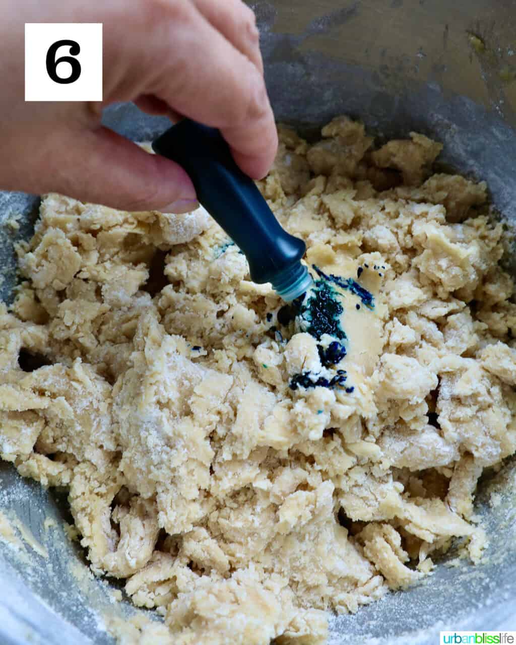 adding food coloring to a bowl with cookie dough.