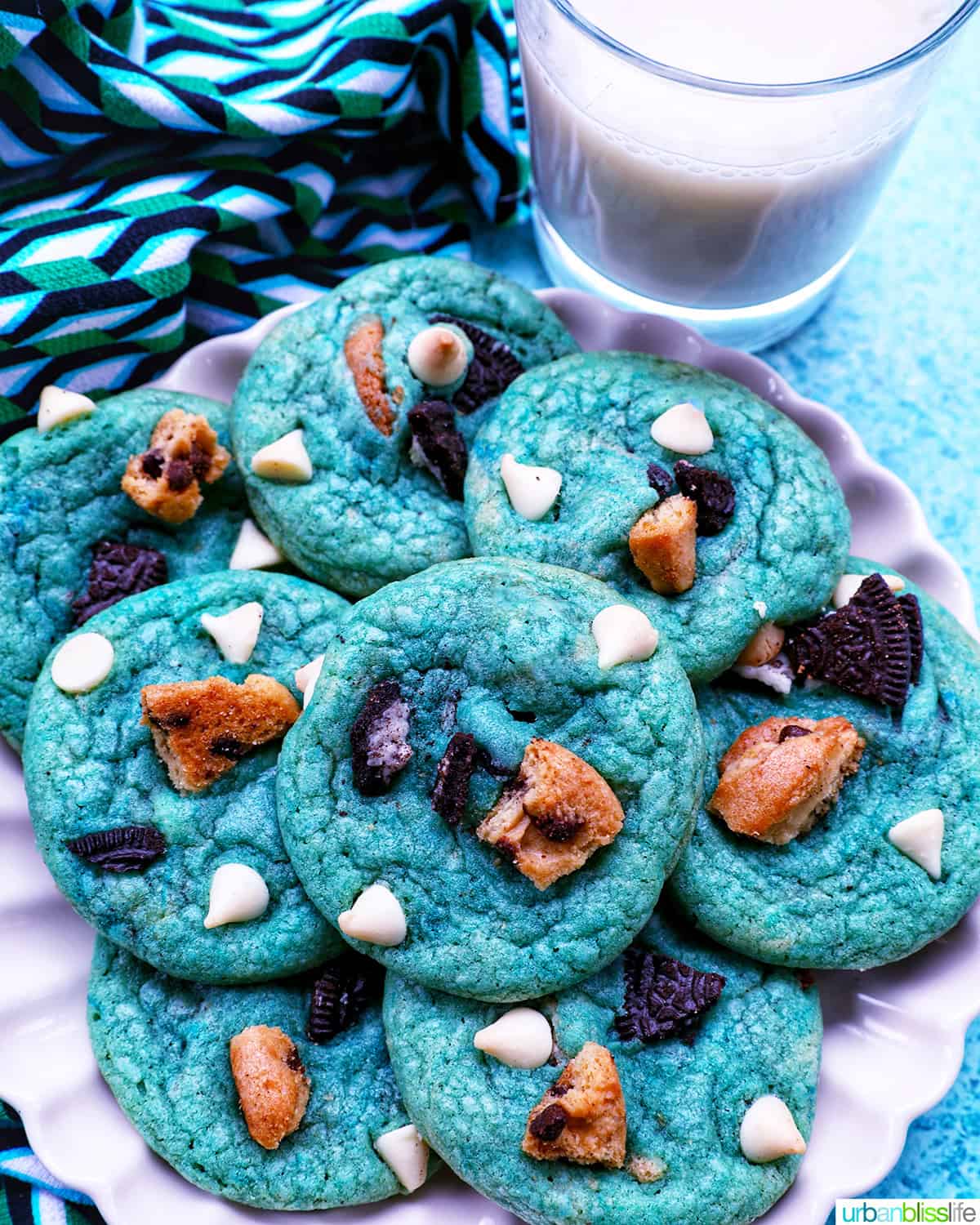 plate full of bright blue Cookie Monster Cookies next to a glass of milk.