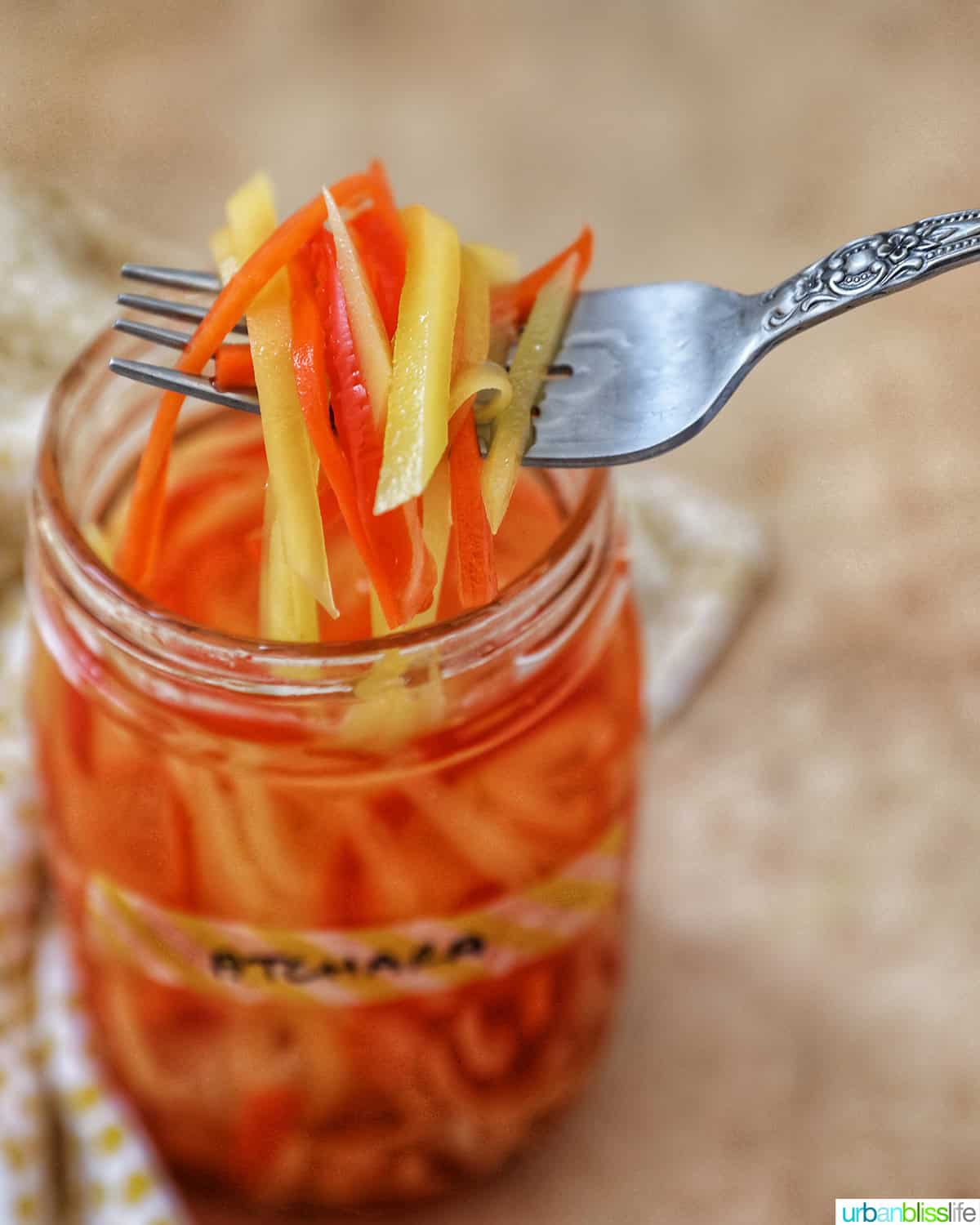 forkful of Filipino atchara condiment - papaya, carrots, red bell pepper, garlic, ginger - over a mason jar.