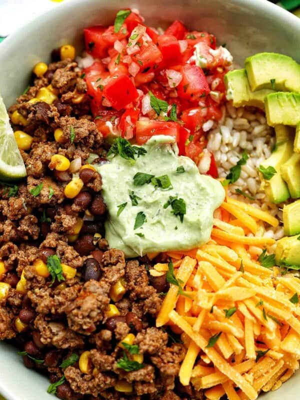 taco bowl with ground beef, beans, cheese, pico de gallo, avocado, rice, avocado cilantro lime crema.