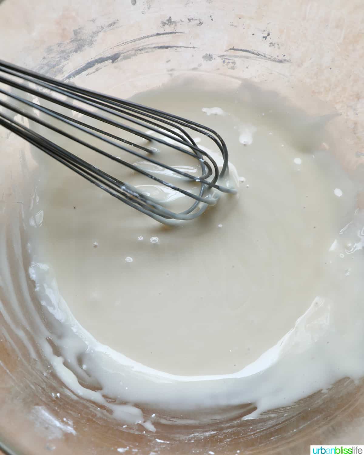 bowl of vanilla glaze with a whisk.