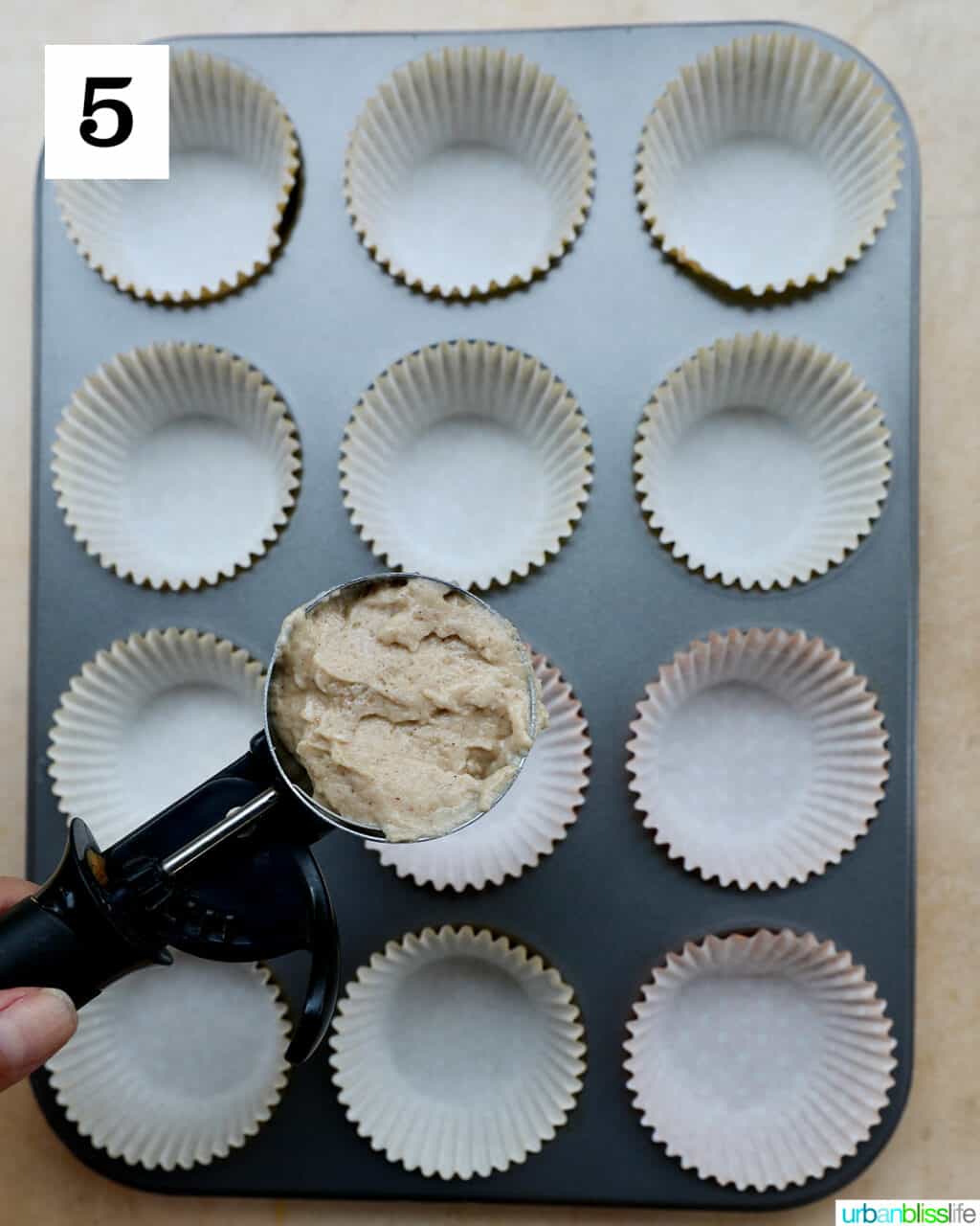 scoop of muffin dough over a muffin tin.