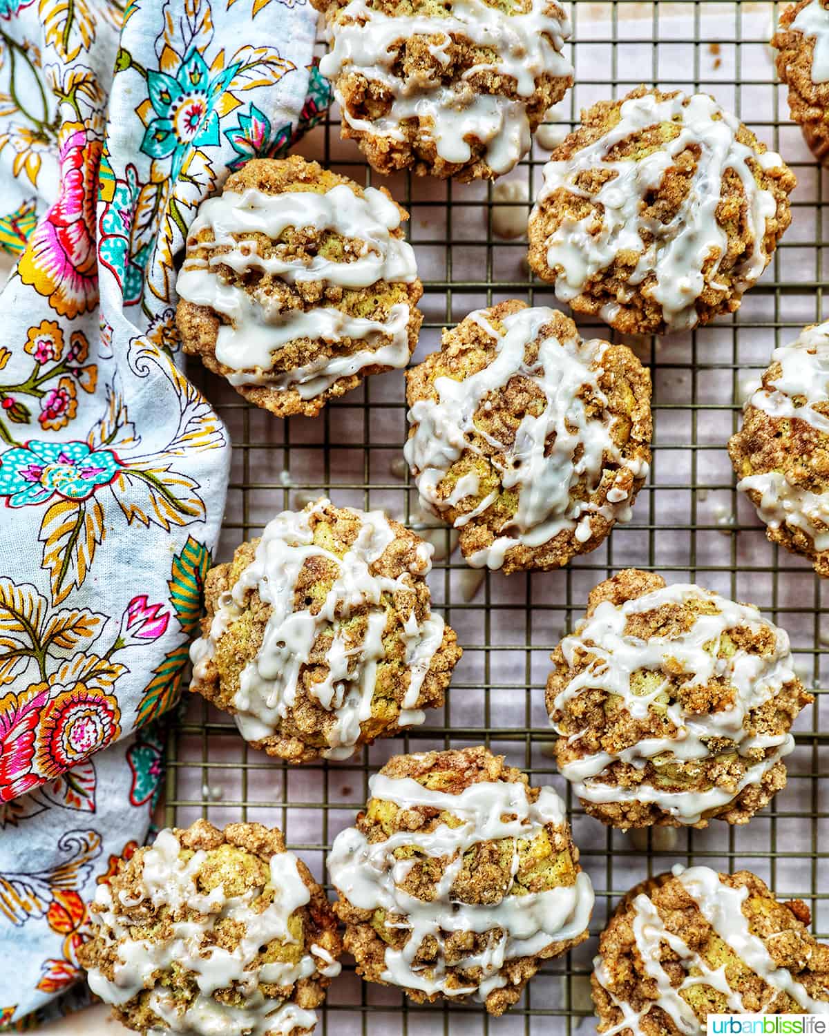 several vegan cinnamon streusel muffins on a wire rack with a colorful floral napkin.