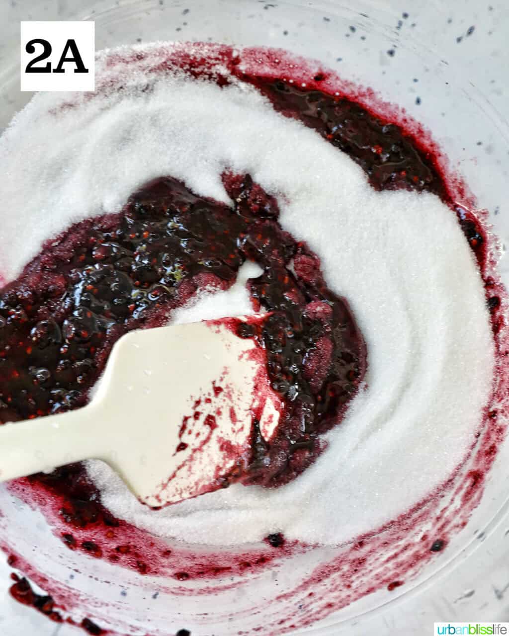 spatula swirling blackberry jam and sugar.