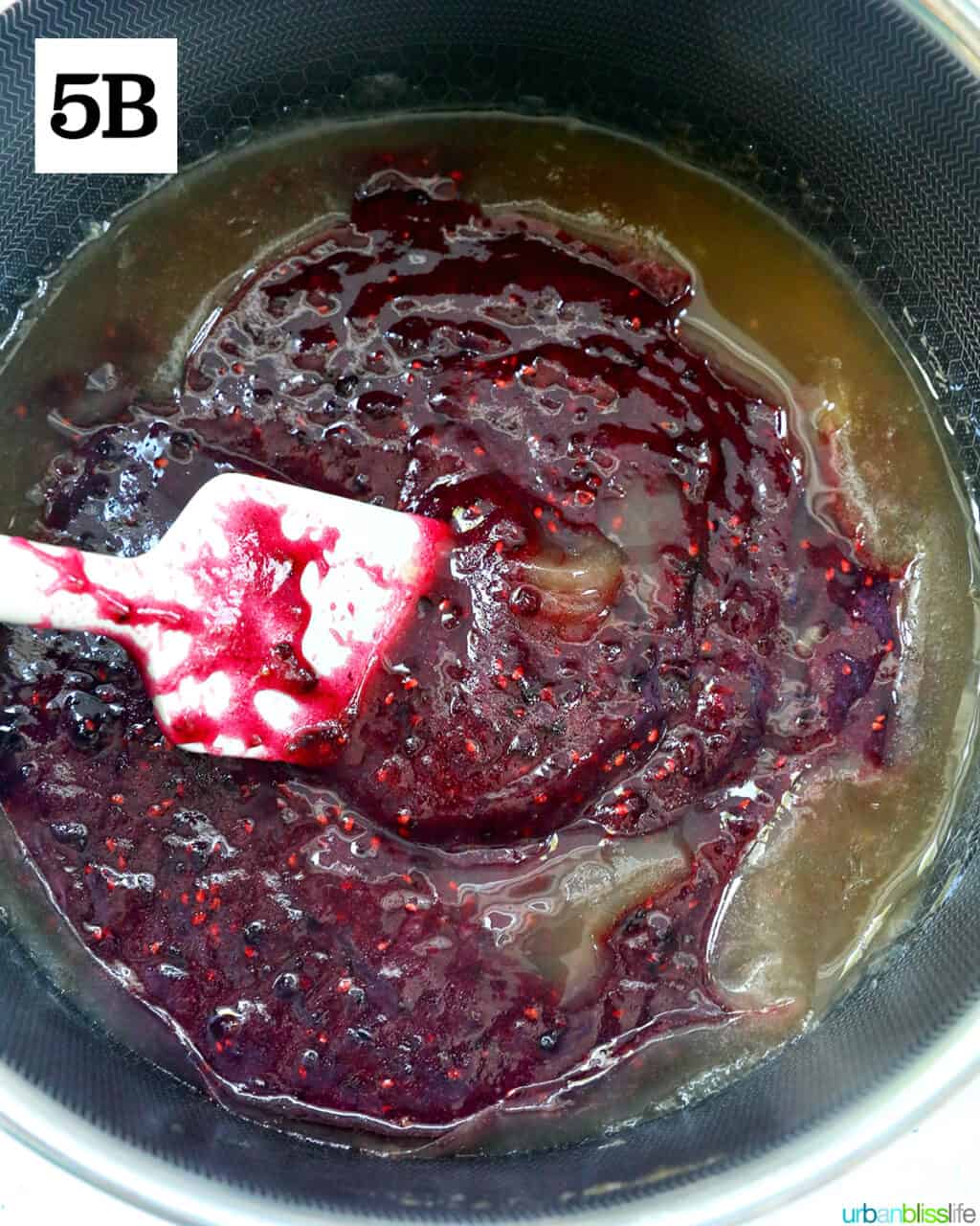 spatula mixing blackberry freezer jam in a saucepan.
