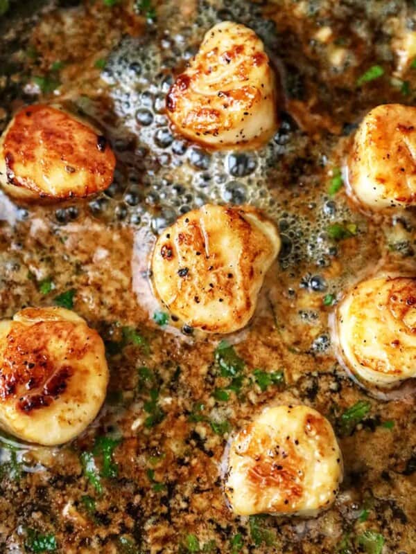 seared scallops in a cast iron skillet with butter garlic herb sauce.