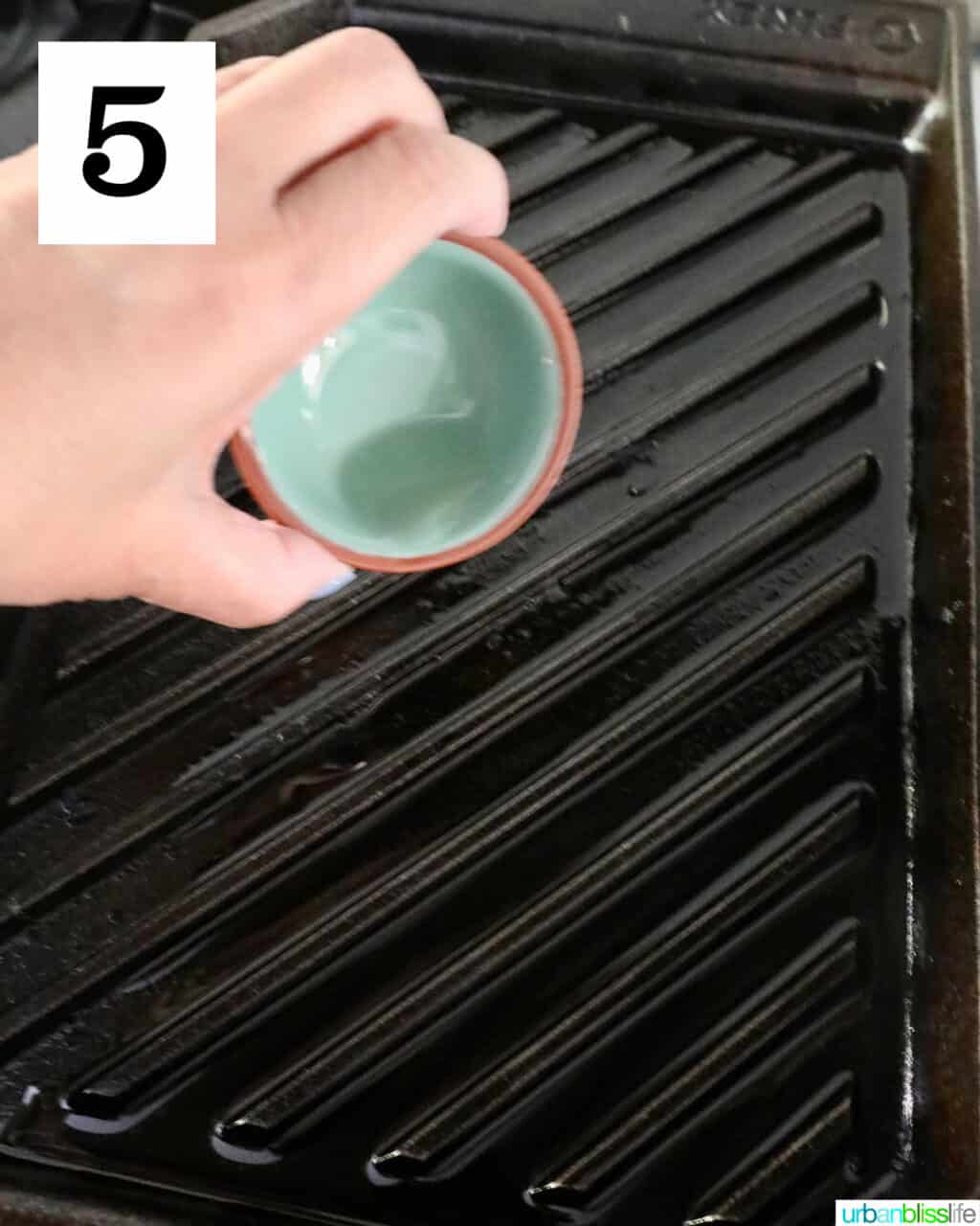 hand pouring oil over a grill pan.