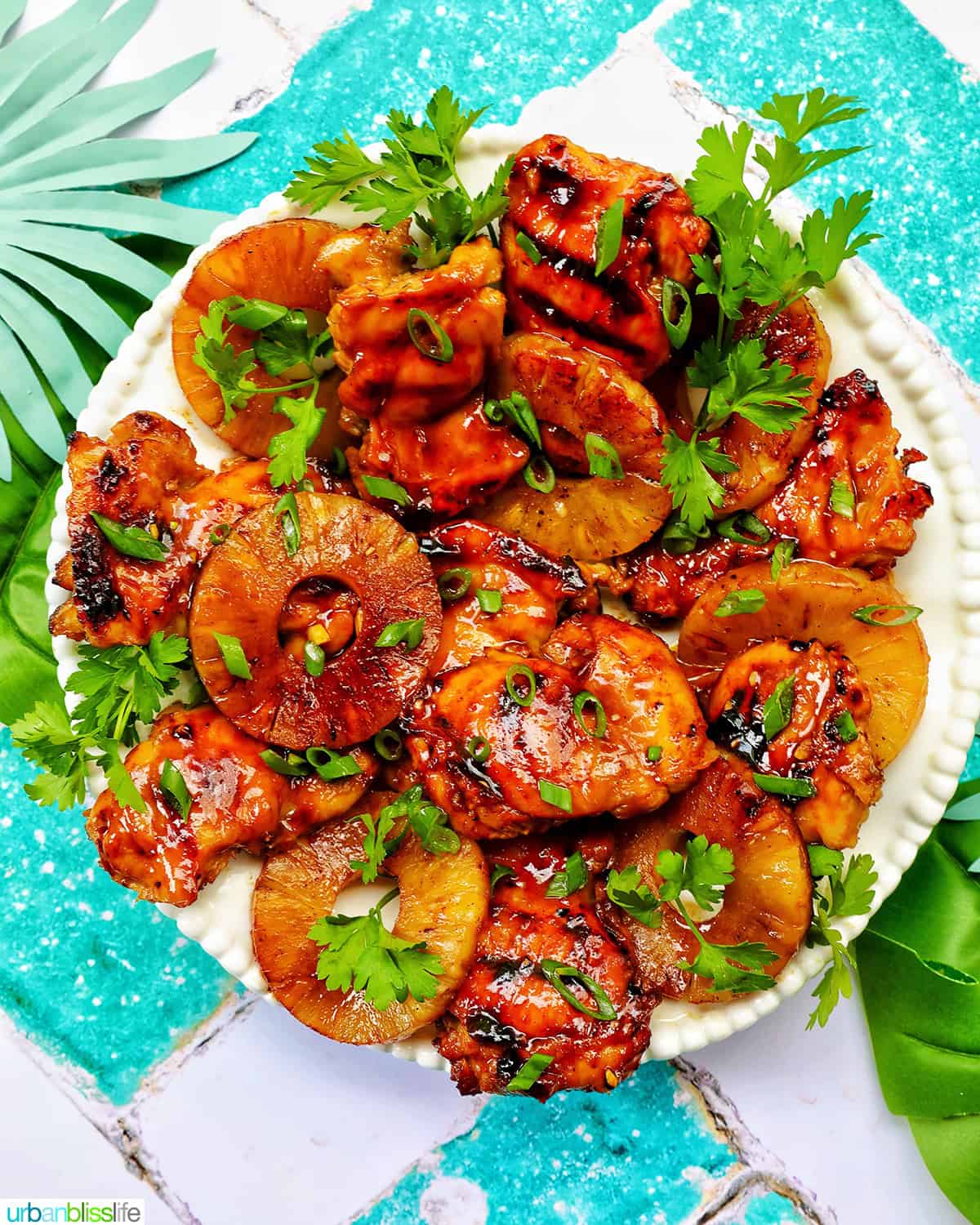 plate of BBQ chicken and pineapples with herbs.