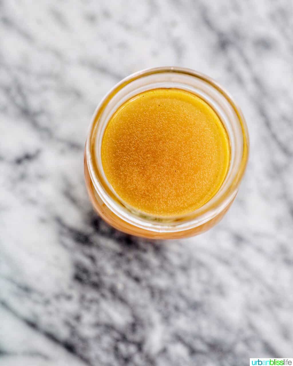 chicken stock in a mason jar on a marble countertop.