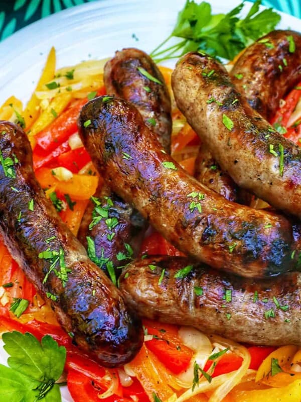 plate of grilled bratwurst over sauteed peppers.