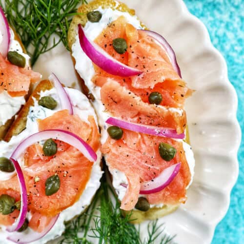 crostini al salmone with garnish of dill on a scalloped plate.