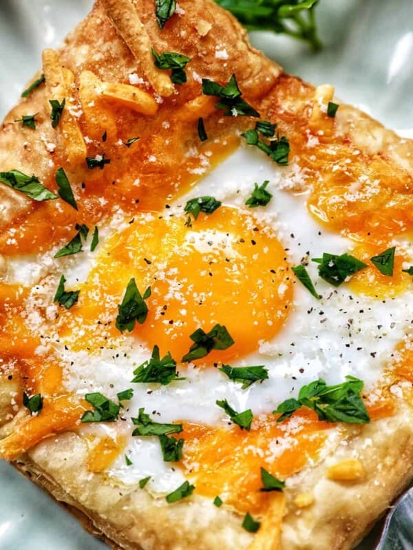 egg in puff pastry on a plate with parsley garnish.