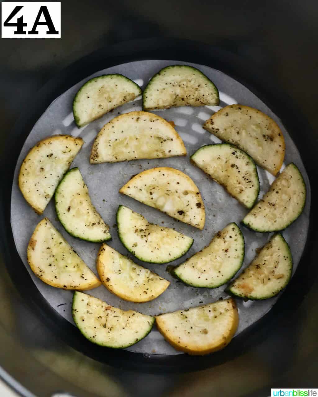 sliced zucchini and yellow squash in an air fryer basket.