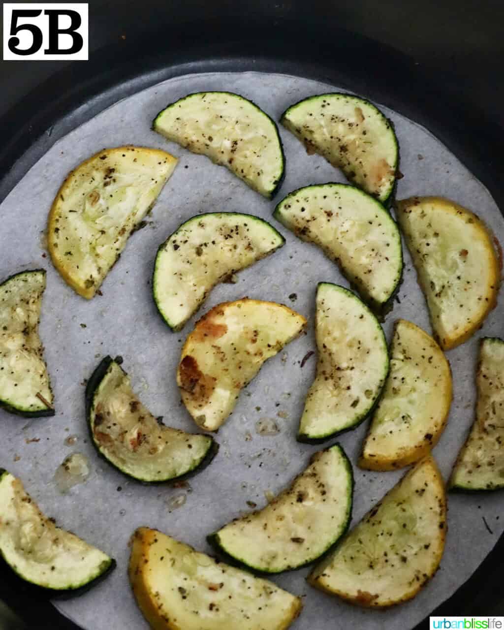 air fried zucchini and yellow squash slices in an air fryer basket.