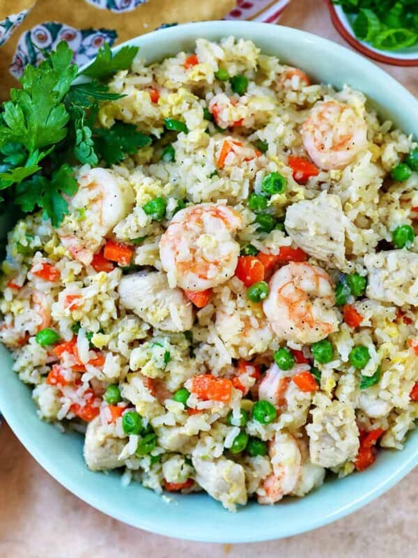 bowl of shrimp and chicken fried rice with side bowl garnish of chopped parsley.