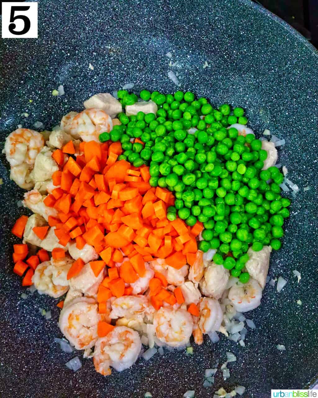 carrots and peas added to a wok with chicken.