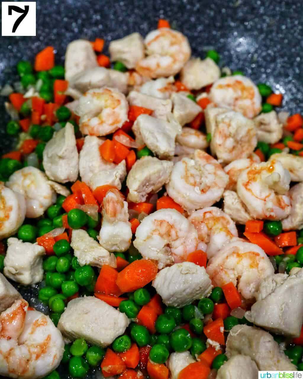 shrimp added to a wok with chicken and vegetables.