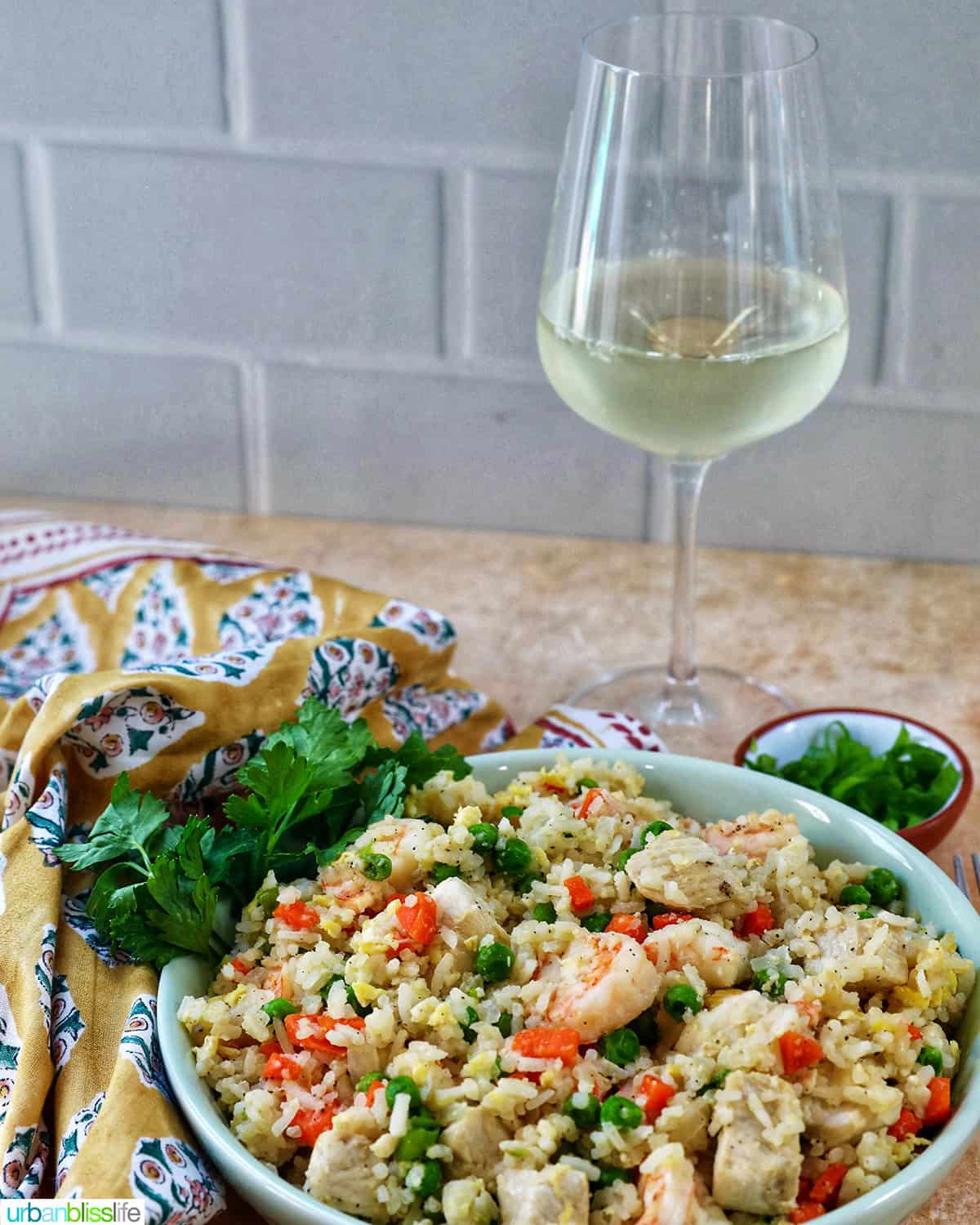 glass of white wine with a bowl of shrimp and chicken fried rice.