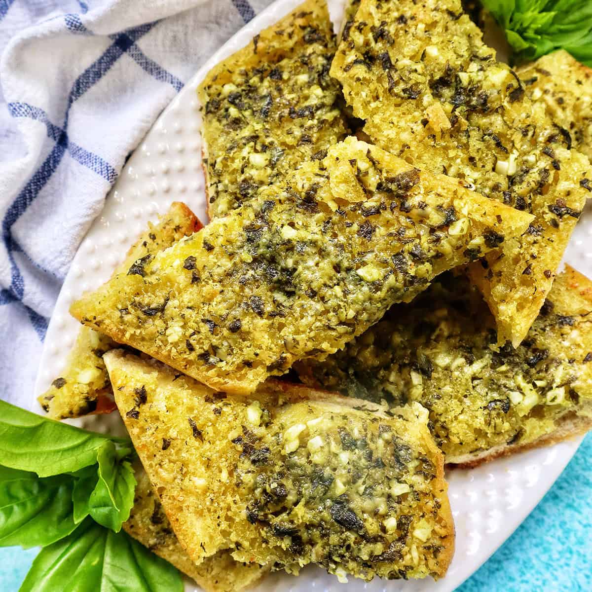 slices of pesto bread on a white platter with garnish of basil.