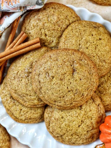 plate full of pumpkin spice cookies with pumpkin decorations and cinnamon sticks.