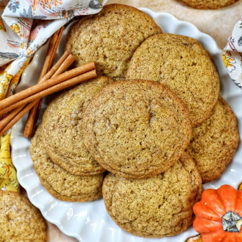 plate full of pumpkin spice cookies with pumpkin decorations and cinnamon sticks.