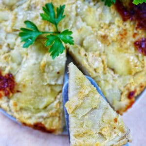 slice of tortilla de patatas taken out of a round Spanish omelette