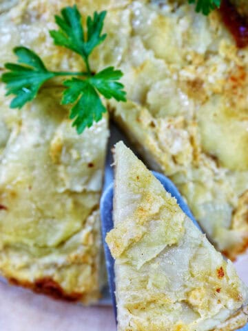 slice of tortilla de patatas taken out of a round Spanish omelette