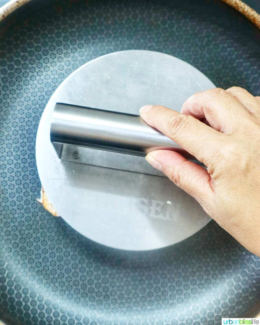 hand pressing down on a sandwich in a pan.