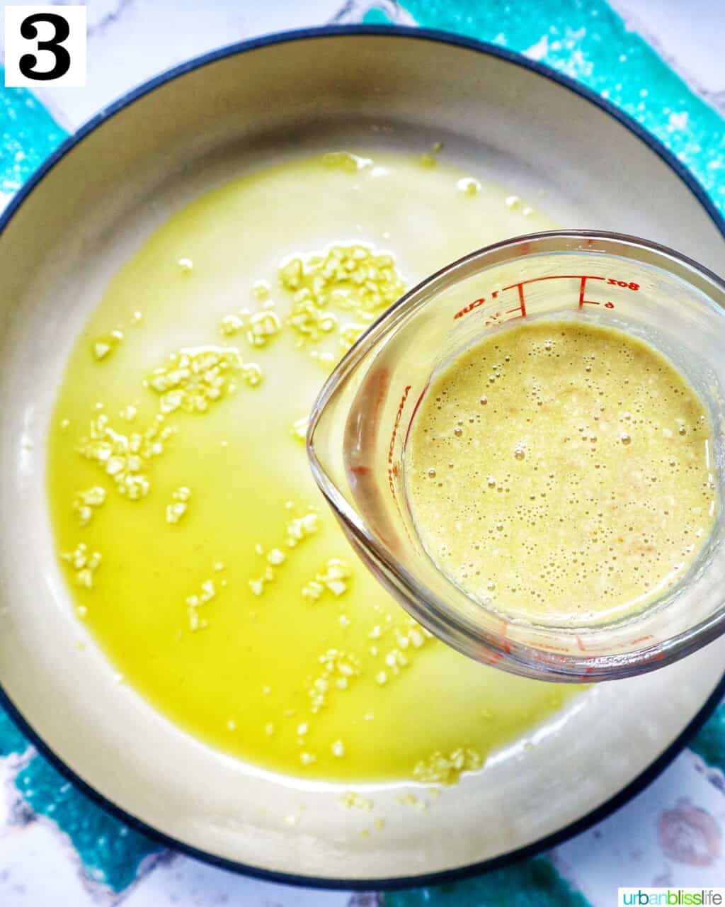 measuring cup of liquid over garlic and olive oil in a saucepan.