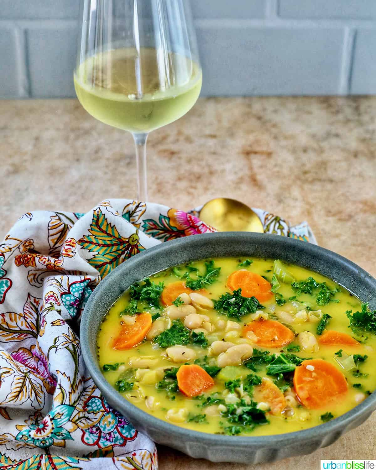 bowl of Tuscan kale and white bean soup with glass of white wine.