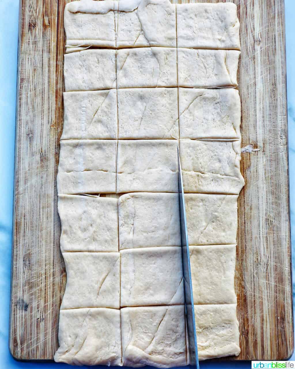 dough cut into small squares on a cutting board.