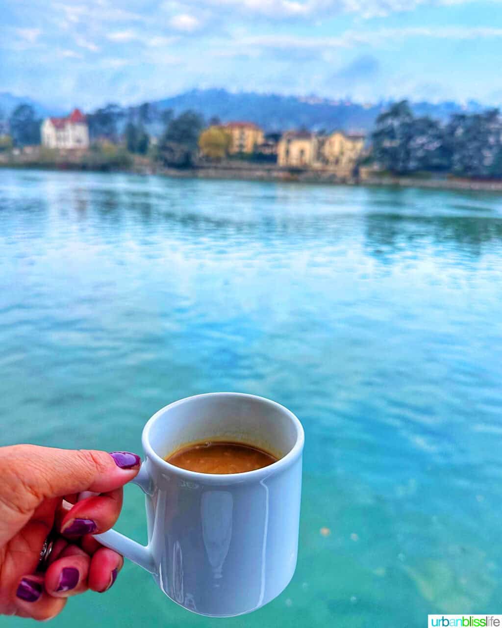 hand holding a mug of coffee from a private balcony on the AmaKristina AmaWaterways river cruise in France.