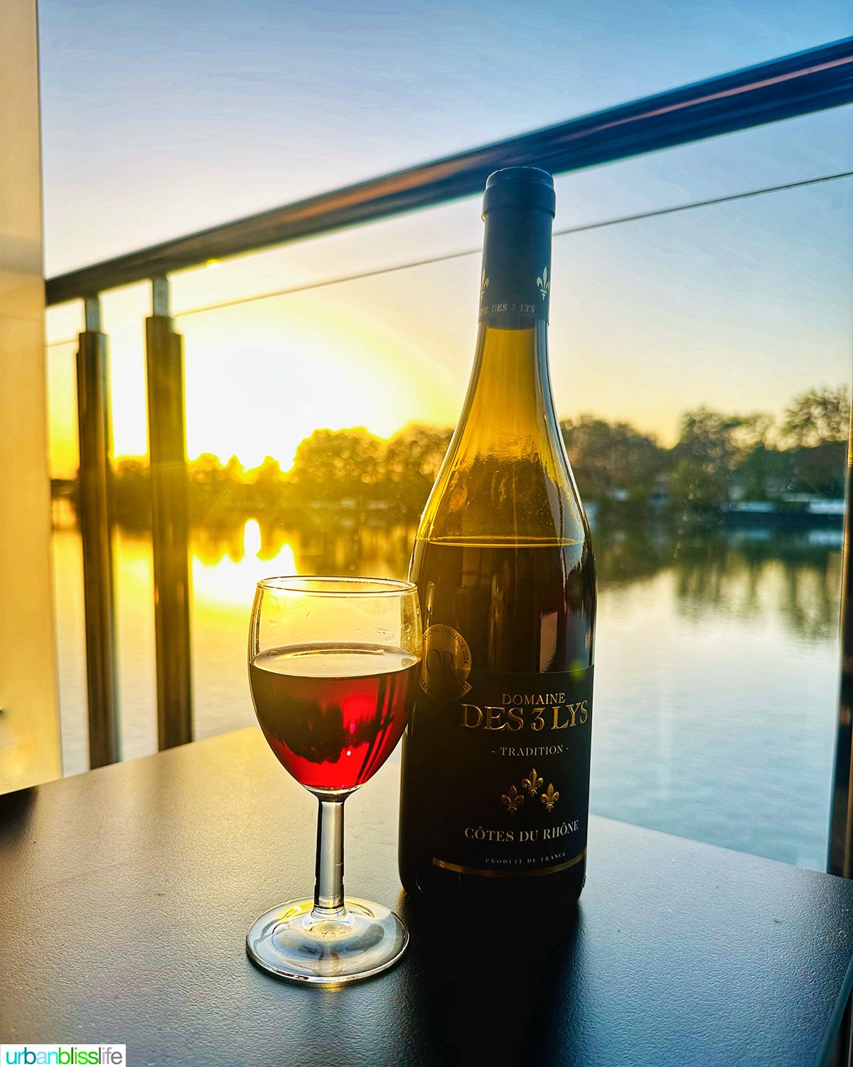 bottle and glass of cotes du rhone red wine on private balcony of aboard AmaWaterways AmaKristina river cruise ship.